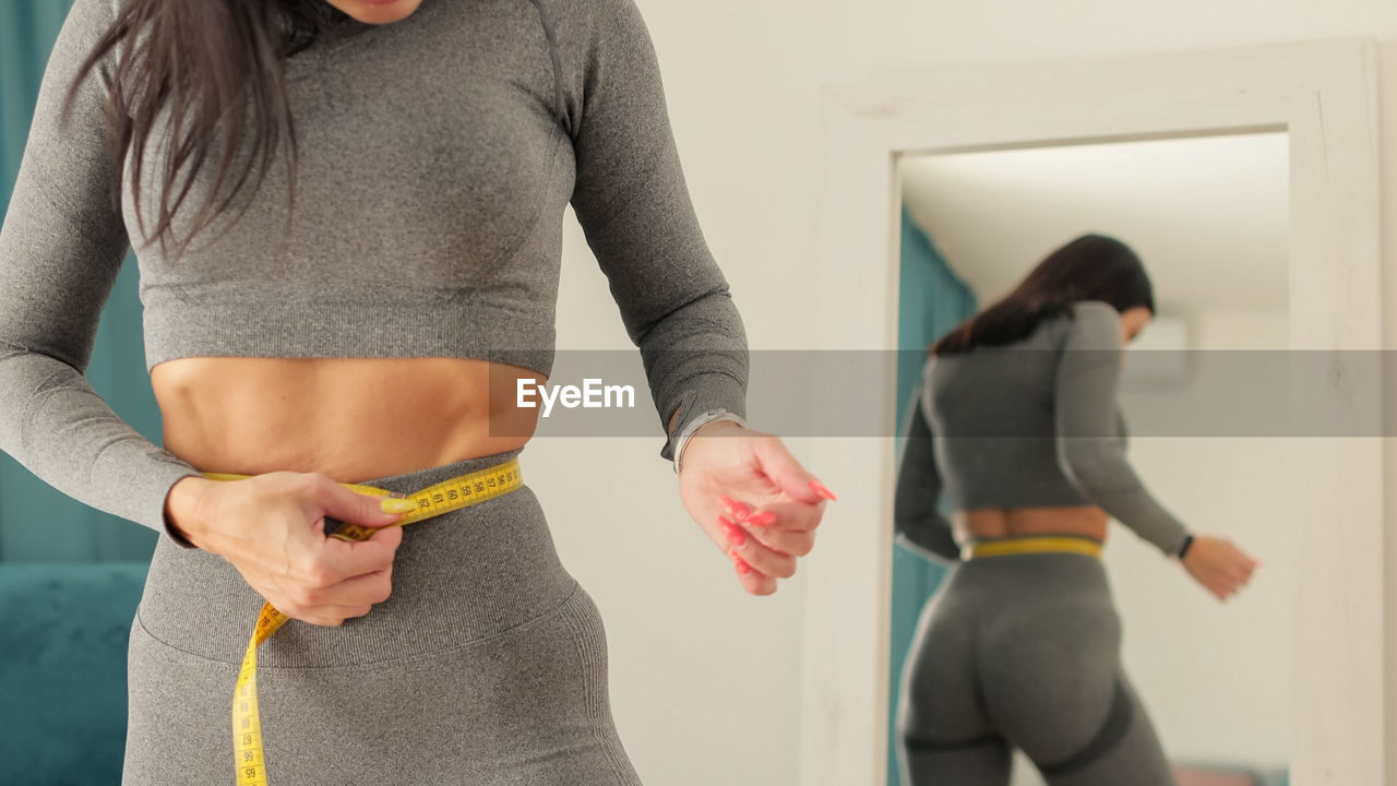 midsection of woman exercising with dumbbells at home