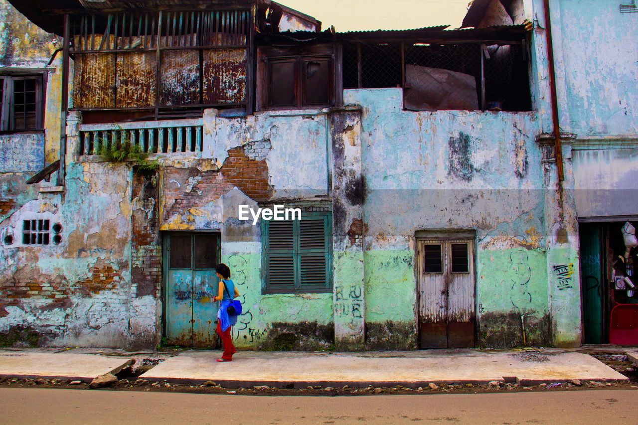 WOMAN WALKING IN FRONT OF BUILT STRUCTURES