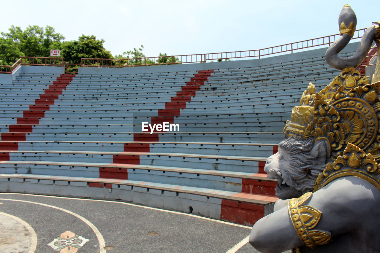 architecture, sky, sport venue, day, religion, adult, belief, outdoors, nature, sculpture, arts culture and entertainment, tradition, built structure, temple - building, one person