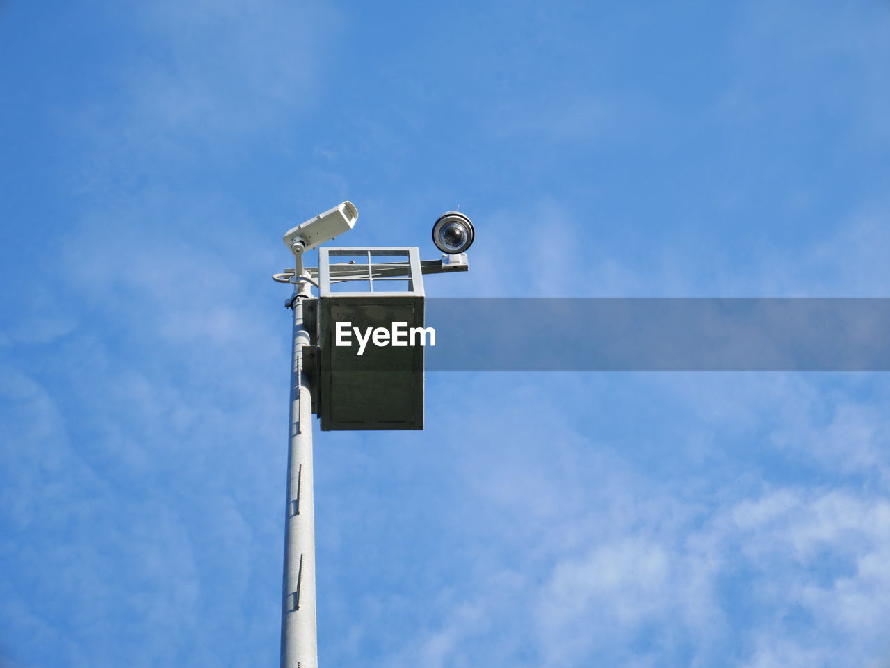 Low angle view of security camera on pole against sky during sunny day