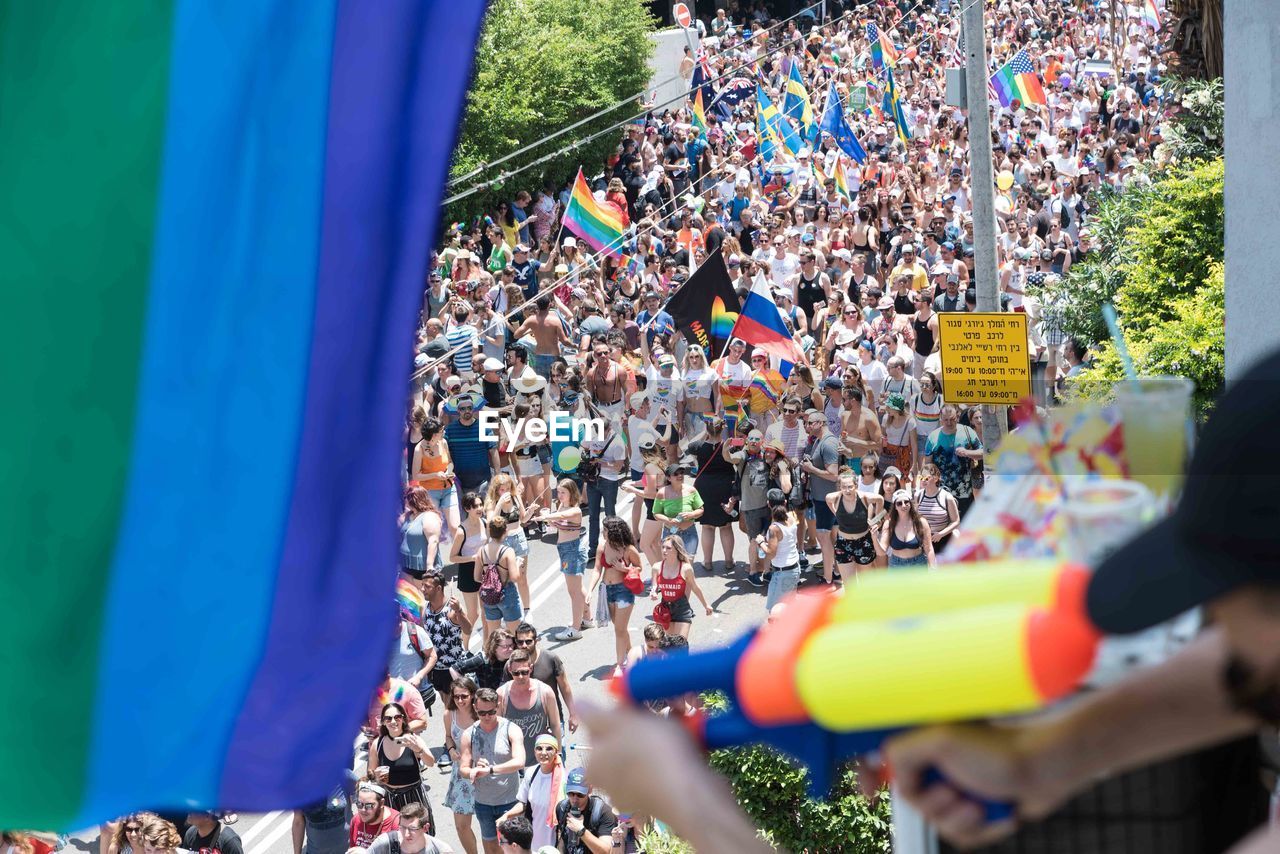 High angle view of people with rainbow flags marching on city street