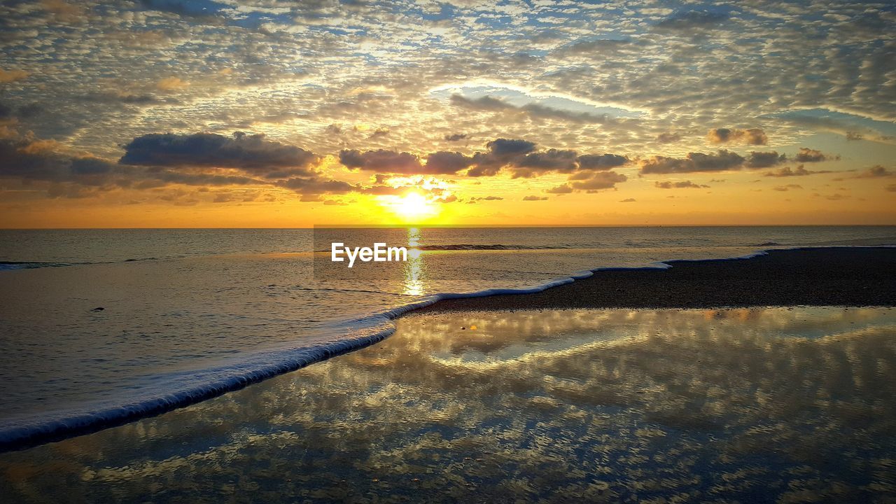 CLOSE-UP OF WET SAND AT BEACH AGAINST SKY