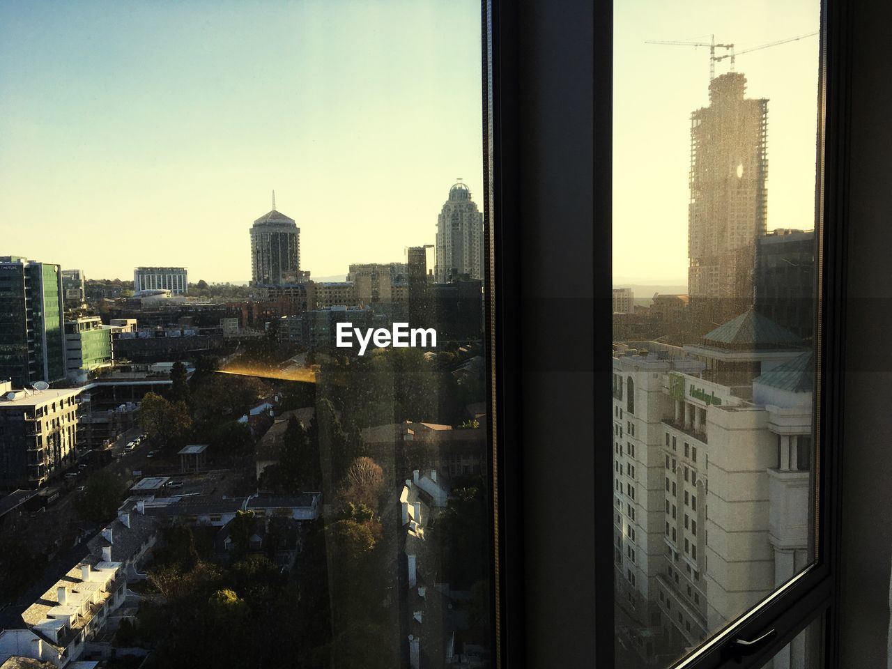 CITYSCAPE AGAINST CLEAR SKY SEEN THROUGH GLASS WINDOW