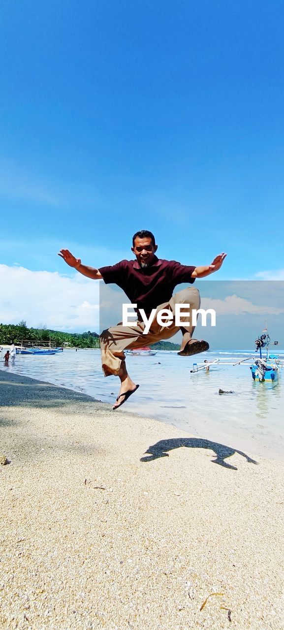 Full length of young man jumping at beach