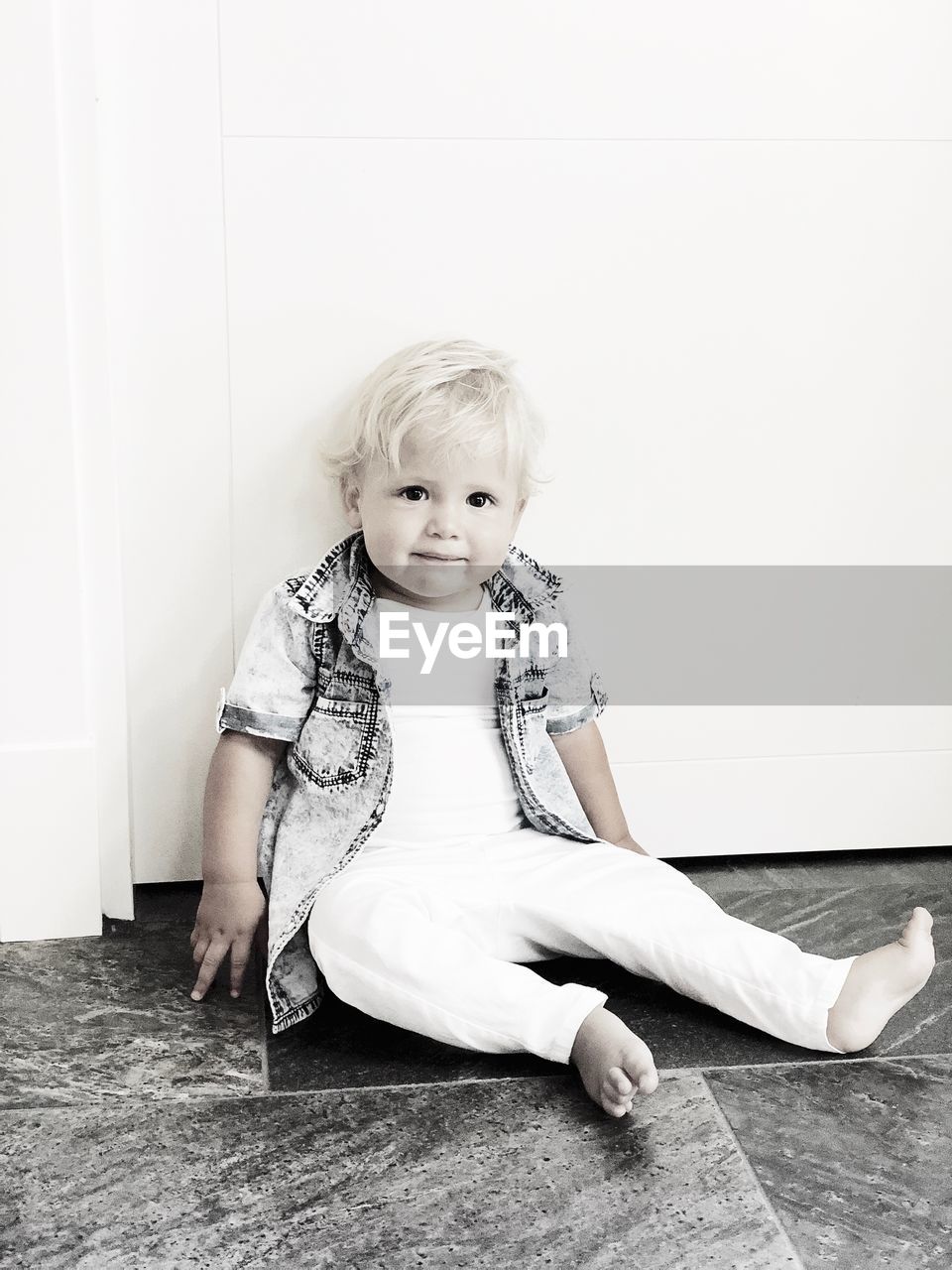 Portrait of cute baby boy sitting against wall