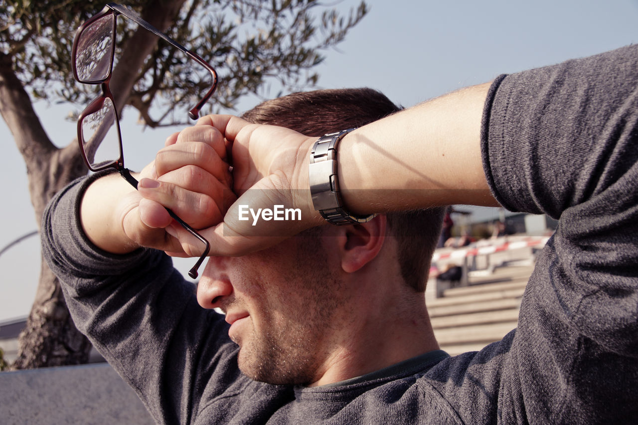 Close-up of young man covering eyes with hands