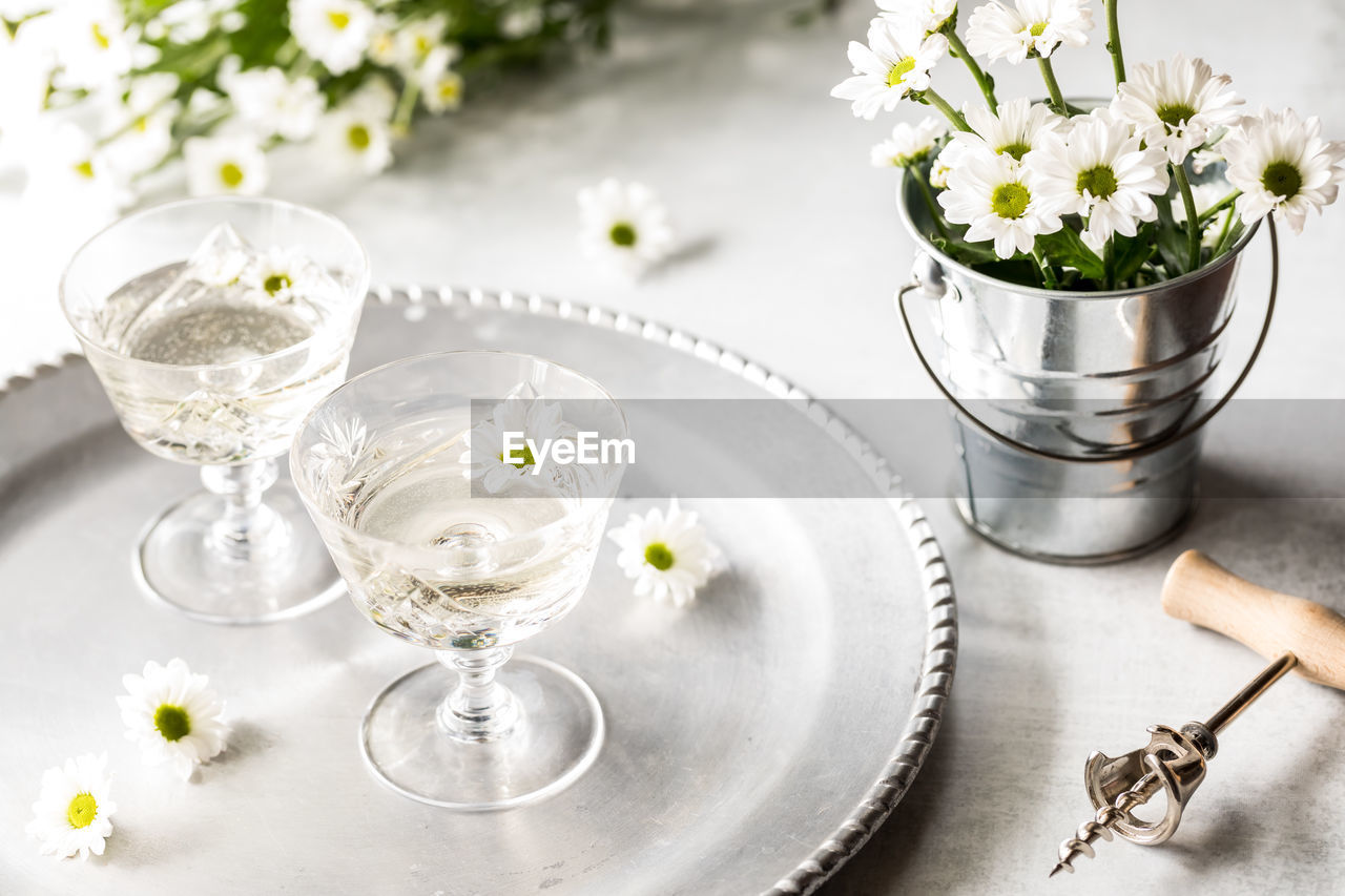 A beautiful scene of glasses of white wine with white daisy flowers,