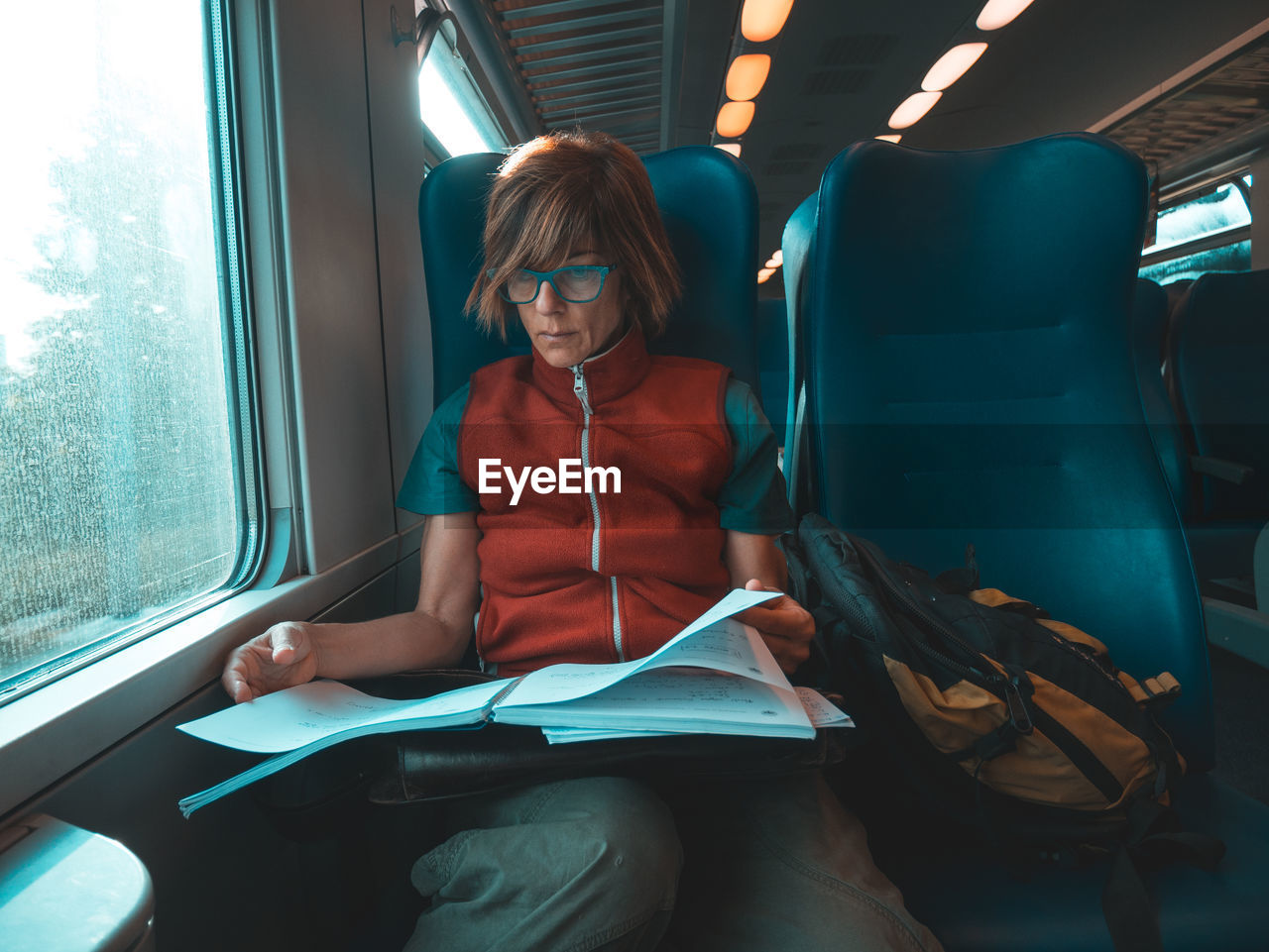 Mature woman reading book while traveling in train