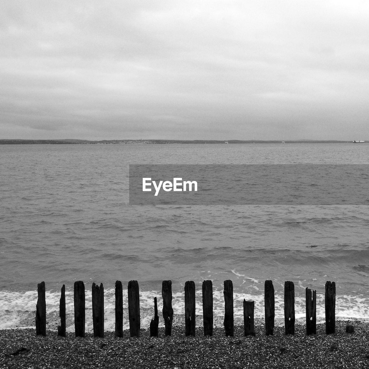 WOODEN POSTS ON SEA AGAINST SKY