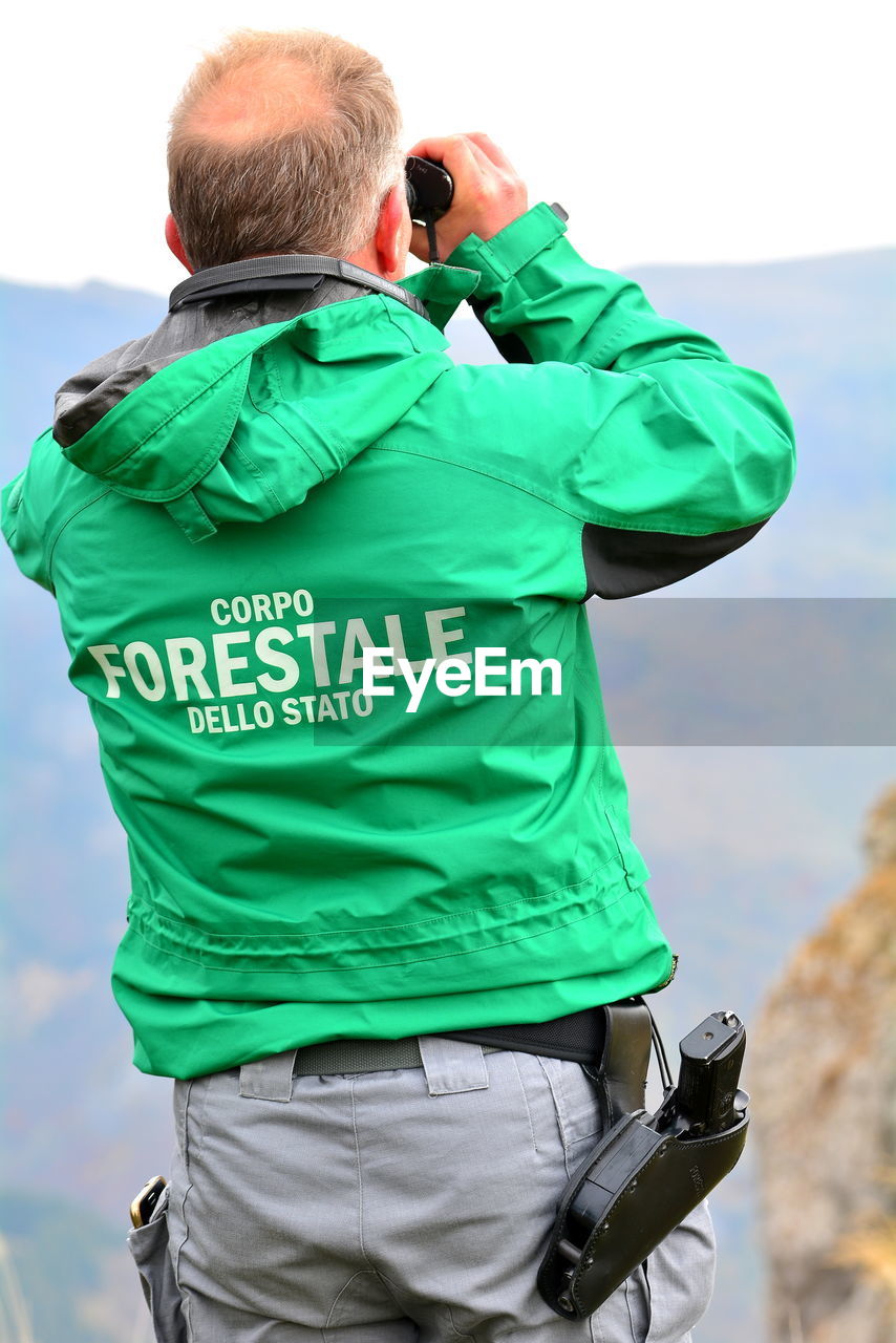 REAR VIEW OF A MAN PHOTOGRAPHING CAMERA