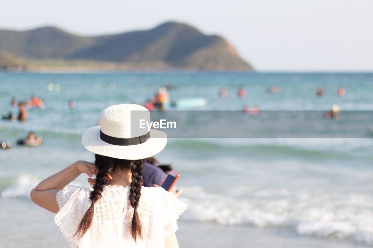 Rear view of girl standing at beach