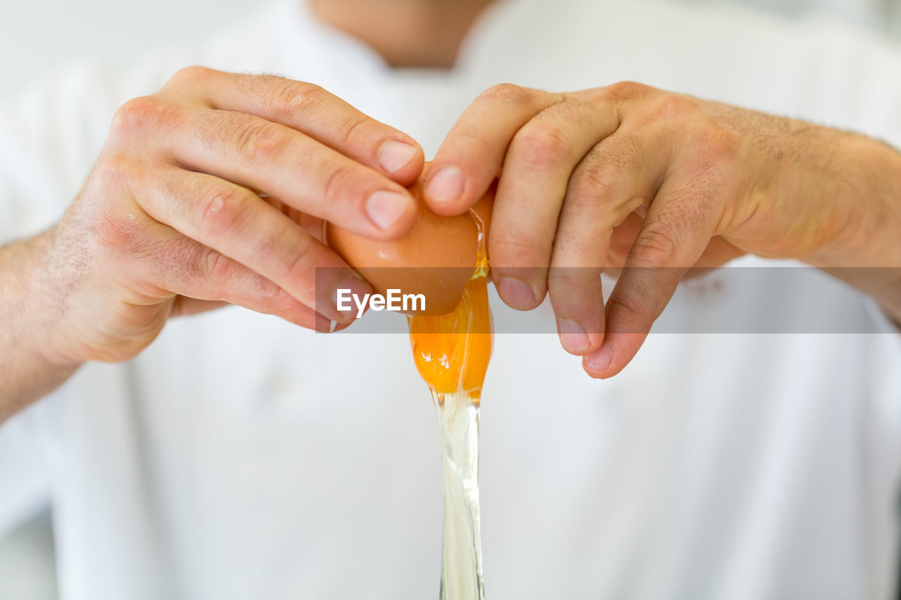 Close-up of hand breaking egg