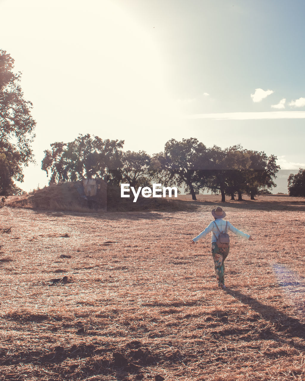 Rear view of woman walking on land against sky