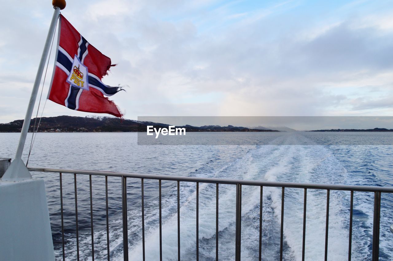 View of norwegian flag on boat at sea against sky