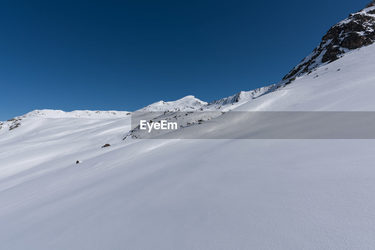 Scenic view of snowcapped mountains against clear blue sky