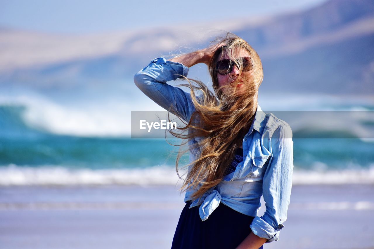 Mid adult woman with tousled hair standing at beach