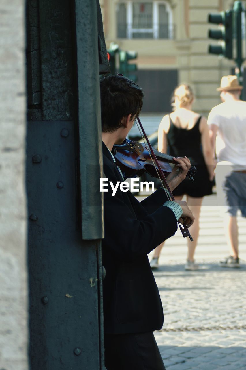 Street musician playing violin against wall