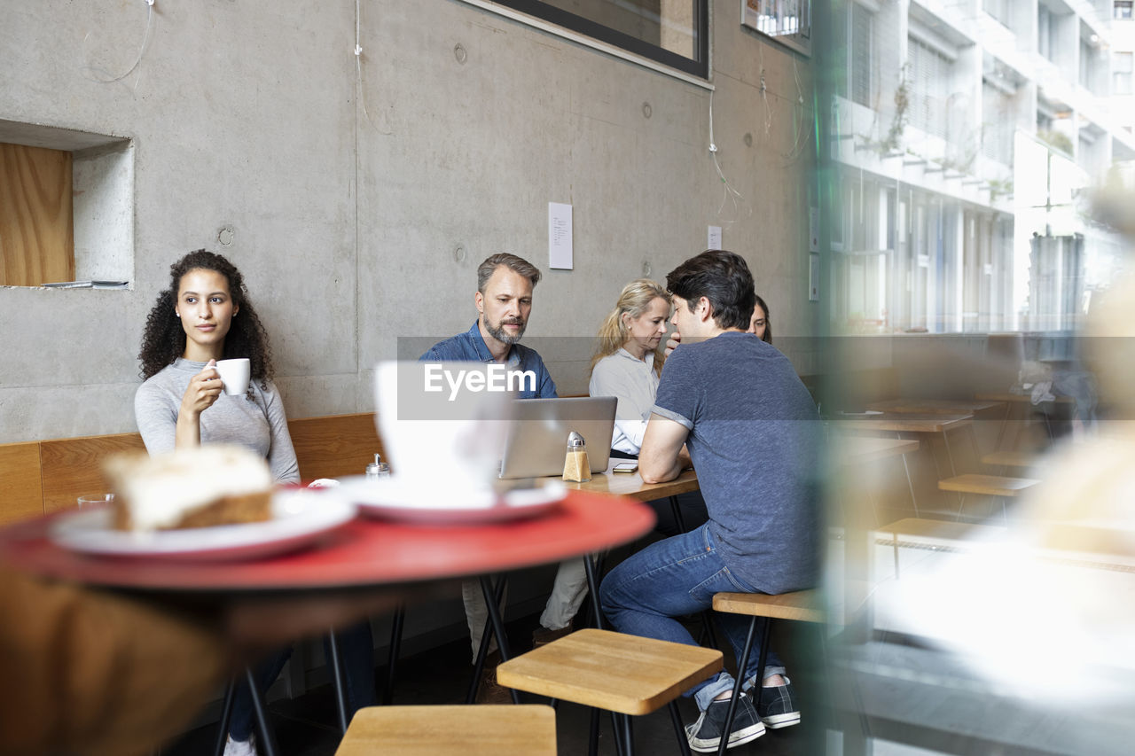 Men and women sitting and having coffee in cafe