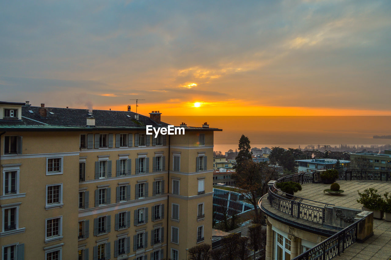 HIGH ANGLE VIEW OF RESIDENTIAL BUILDINGS AGAINST SKY DURING SUNSET