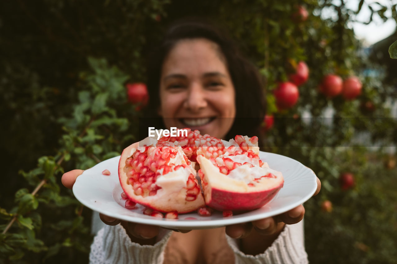 PORTRAIT OF SMILING WOMAN HOLDING STRAWBERRY