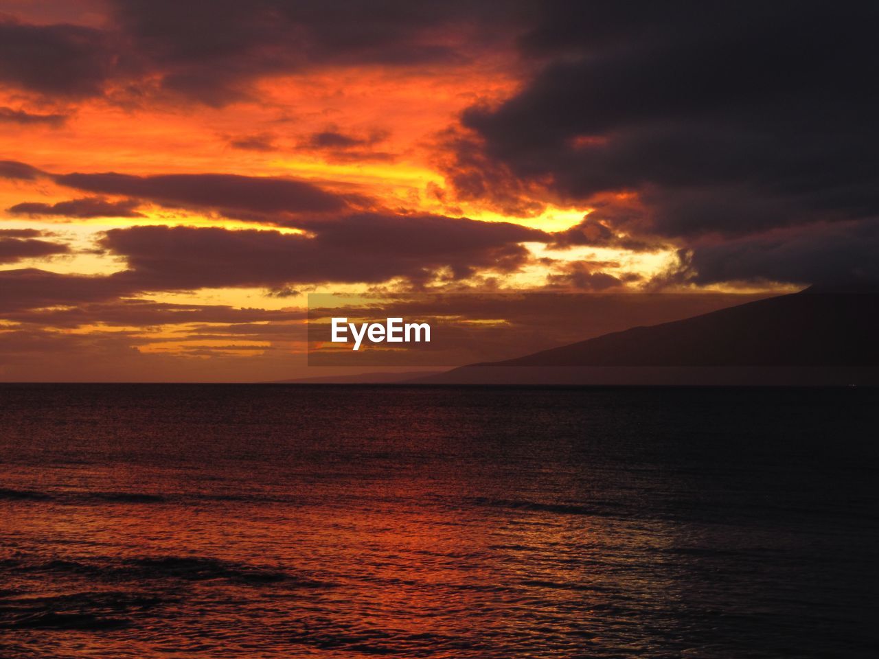 Scenic view of sea against dramatic sky during sunset