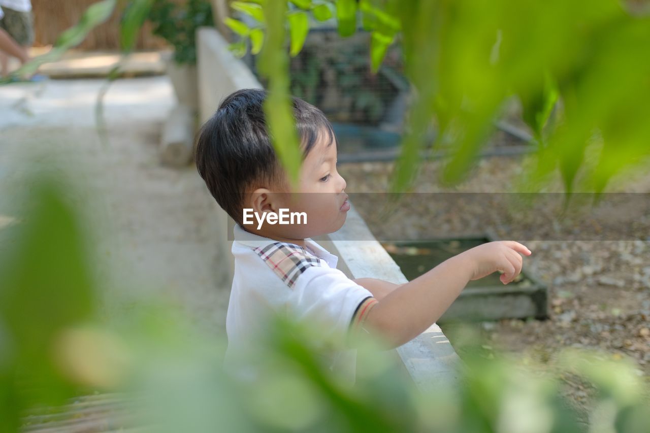 side view of boy looking away while sitting on field