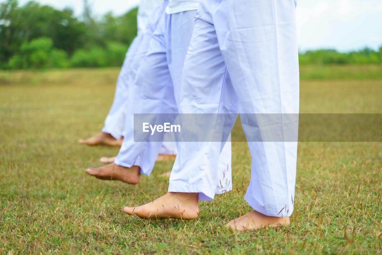 low section of people standing on grassy field