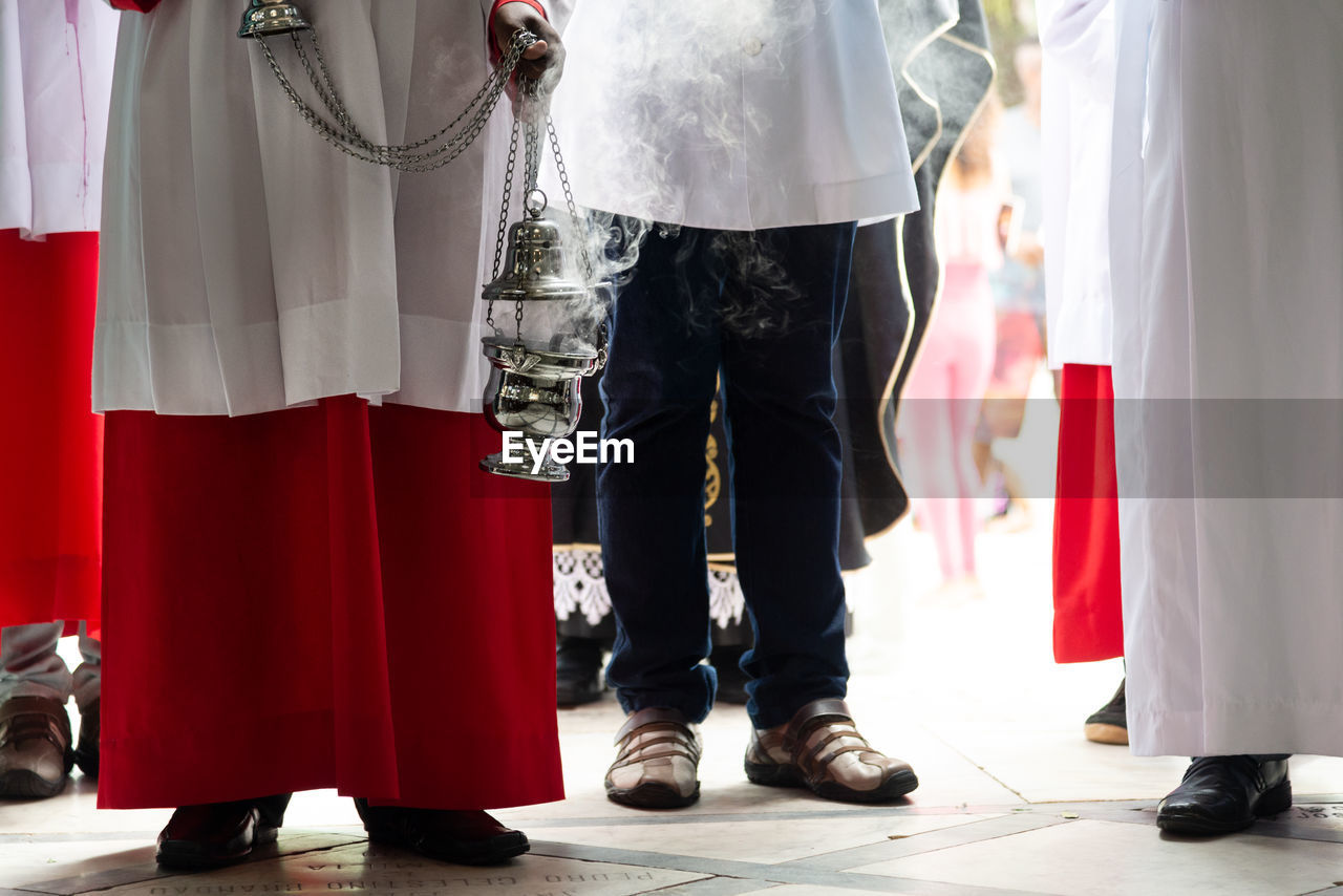 Lower part of catholic church members with incense in the campo santo cemetery church 
