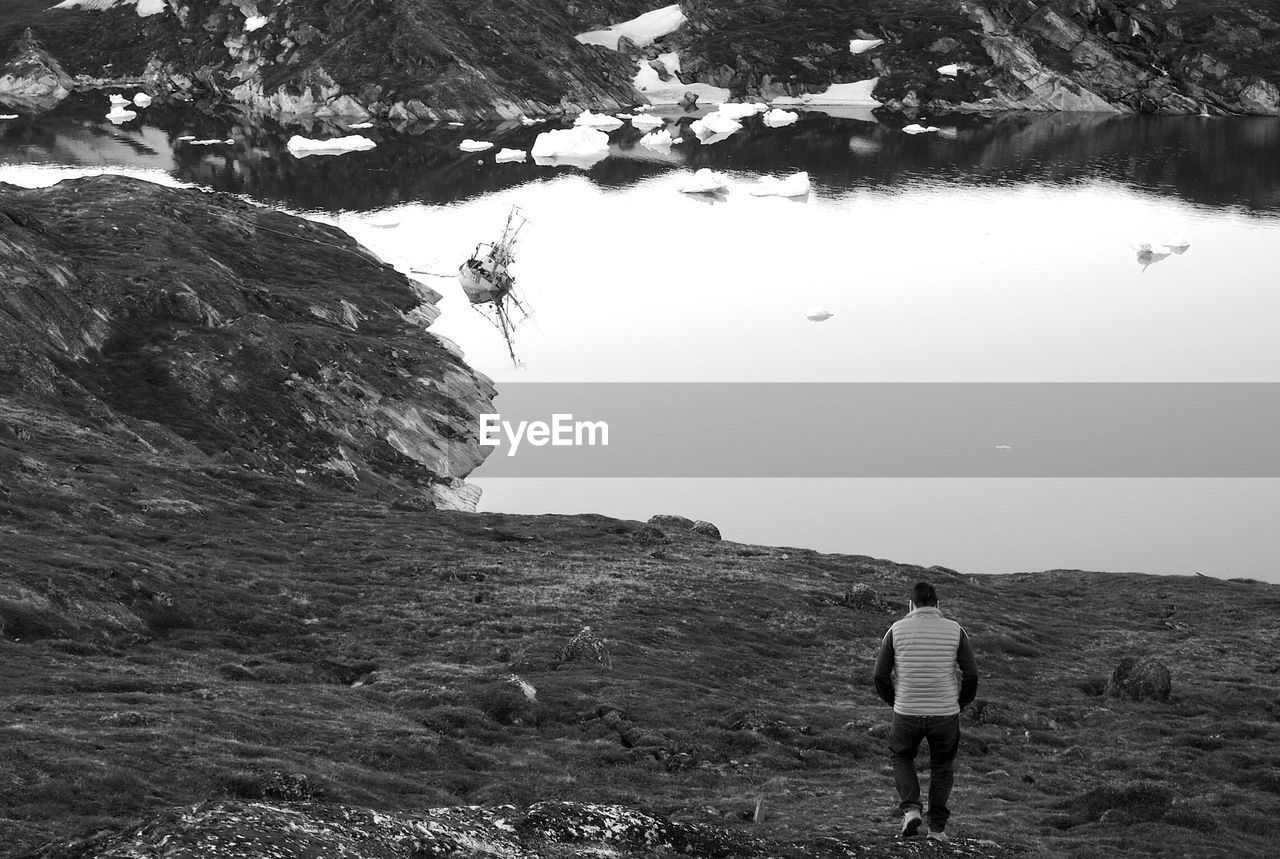 Man walking alone towards river in winter