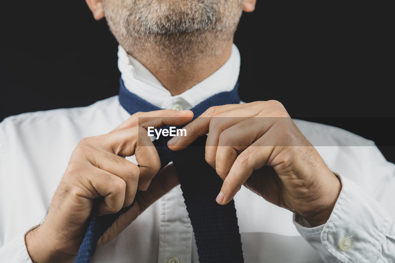 Midsection of man making face against black background