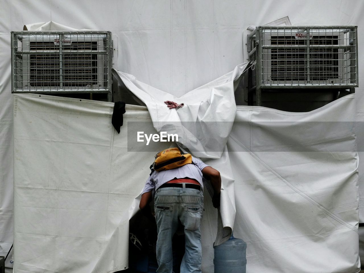 Rear view of man entering in building covered with plastics at construction site