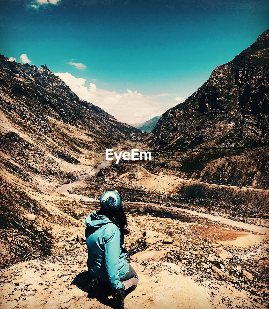 Woman looking at mountain while kneeling on ground