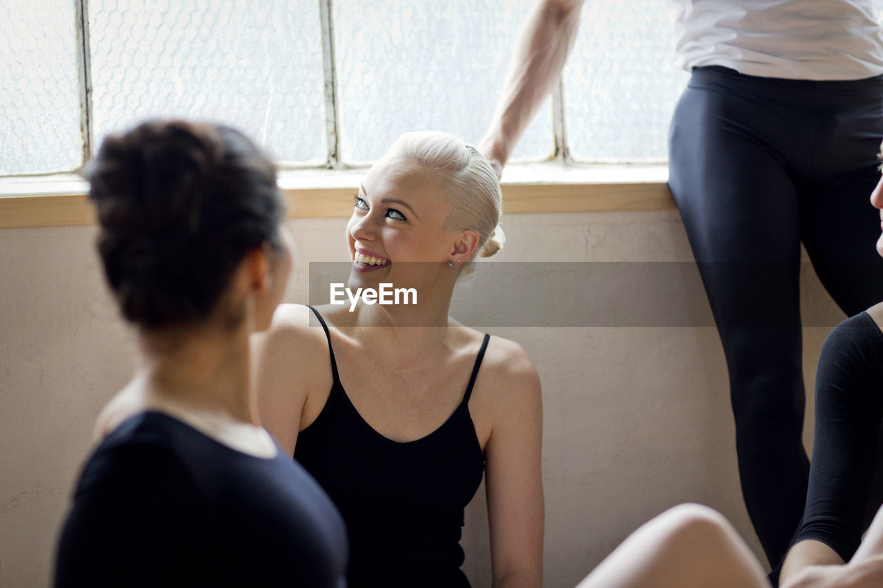 Smiling friends relaxing in ballet studio