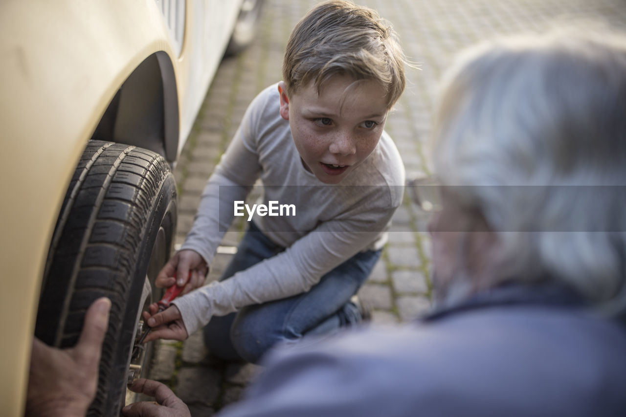 Senior man and boy changing car tire