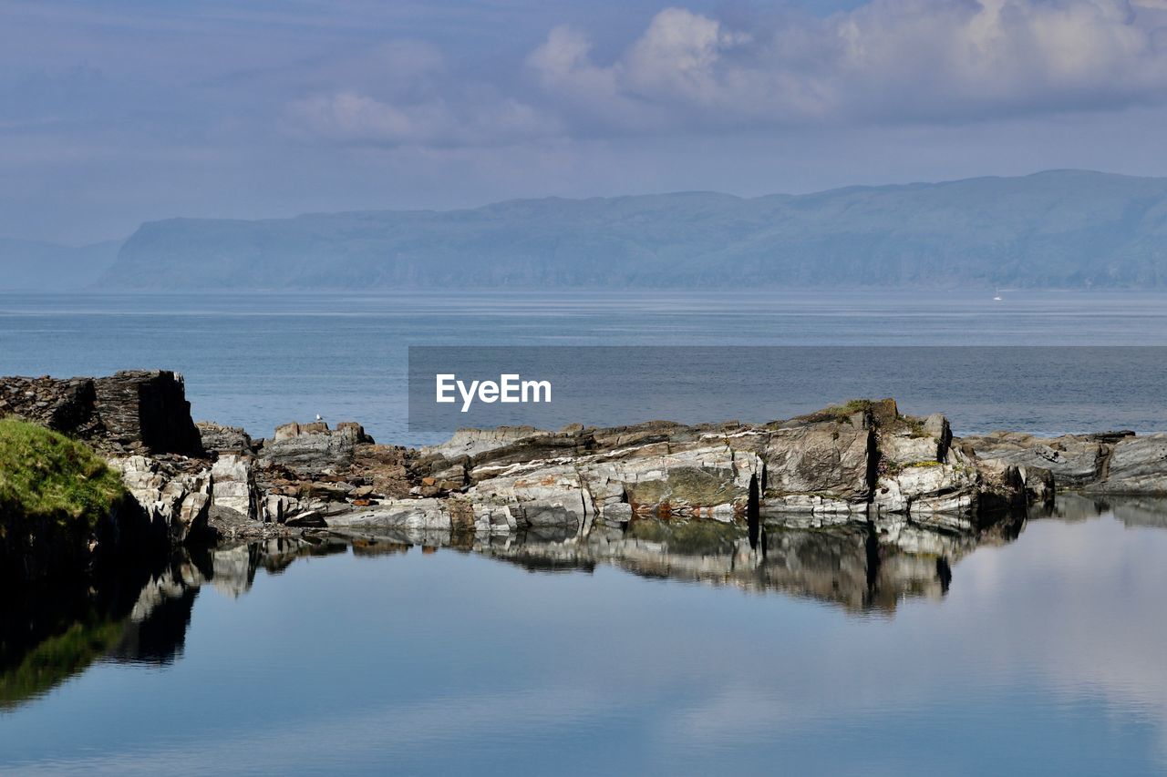 Scenic view of sea by mountains against sky