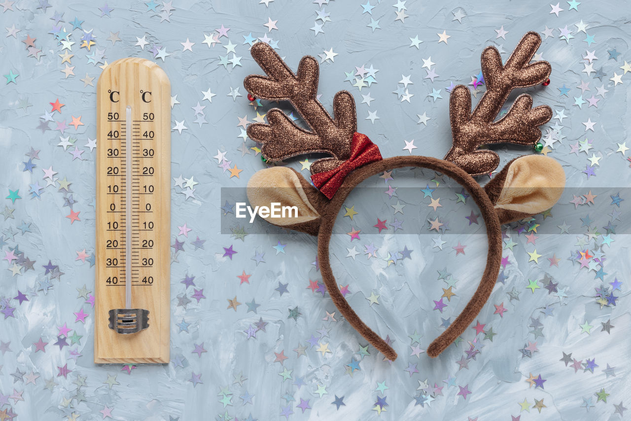 Thermometer shows low temperature and christmas deer headband costume on blue and white