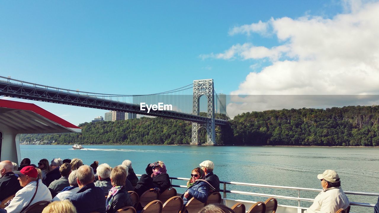 Tourist on boat in front of suspension bridge over river