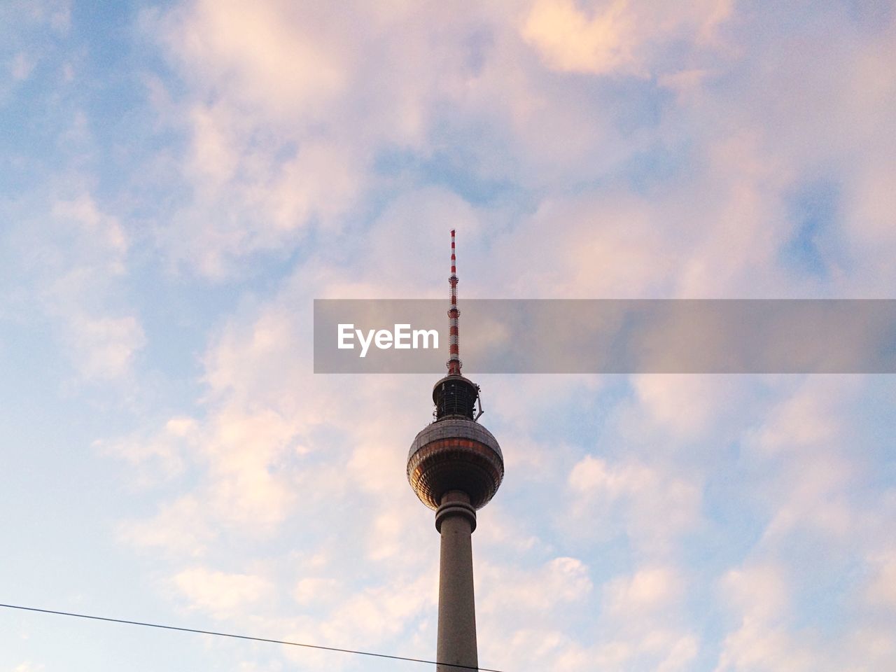 Low angle view of fernsehturm against cloudy sky