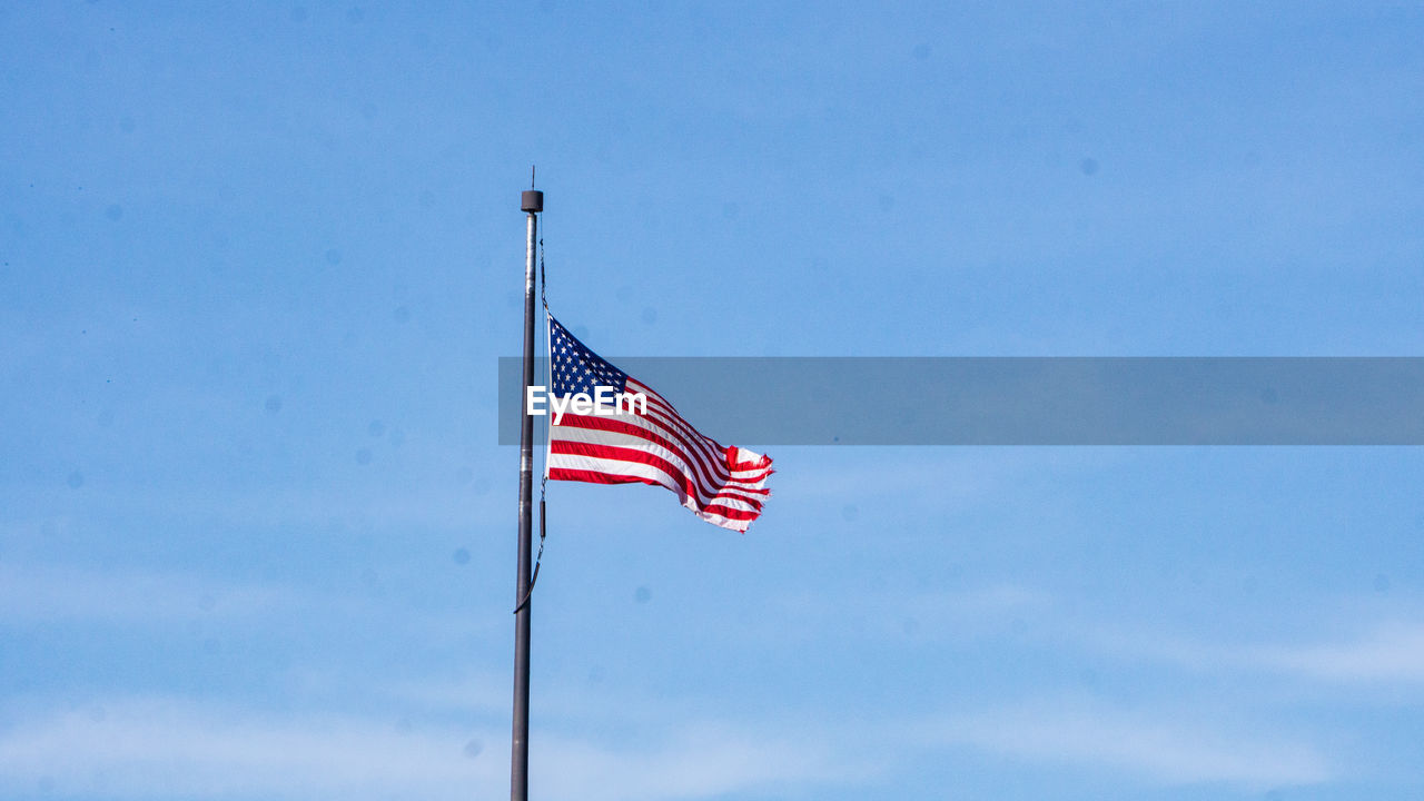 Low angle view of flag against blue sky