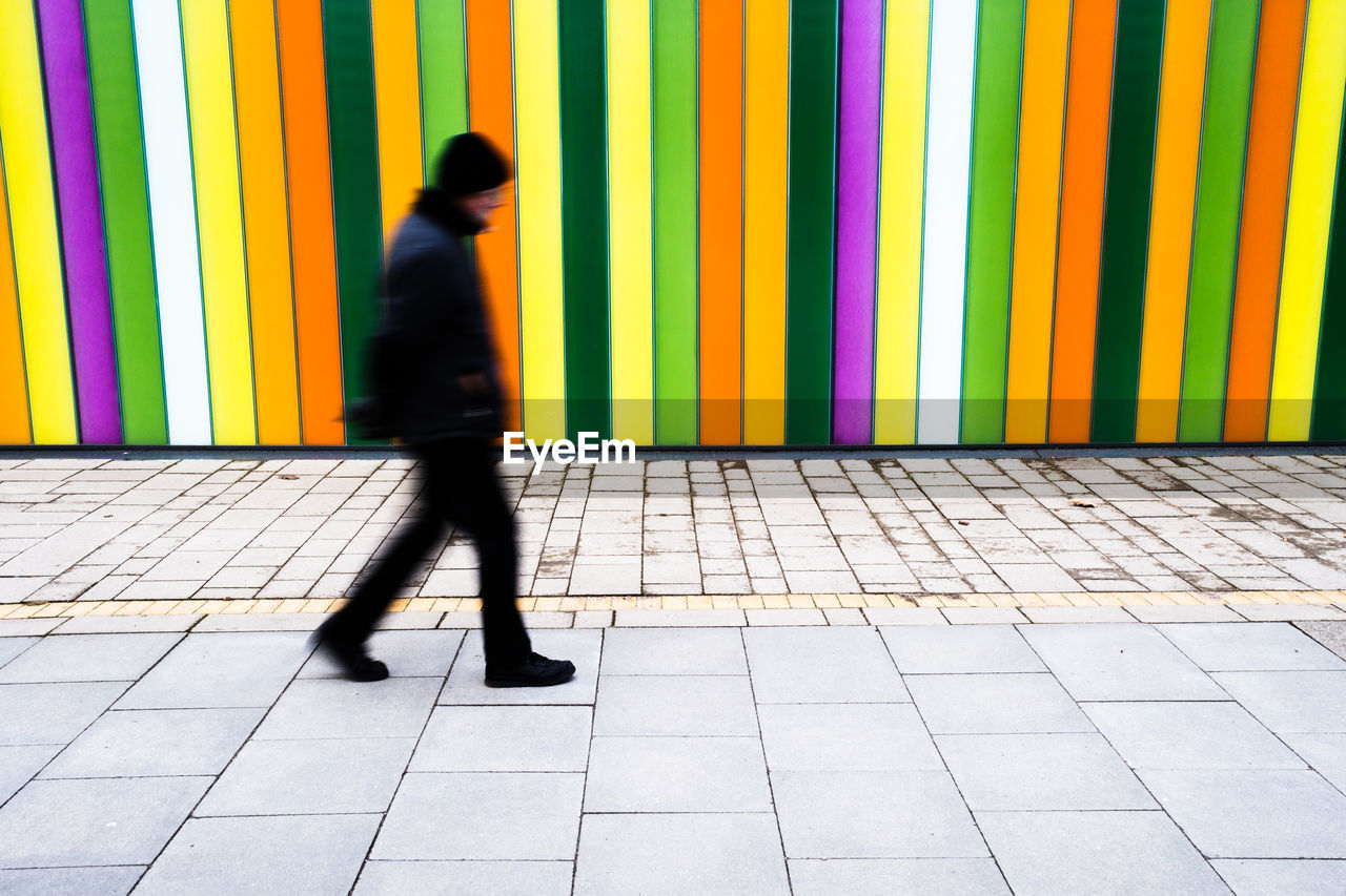 FULL LENGTH OF A MAN WALKING ON FOOTPATH