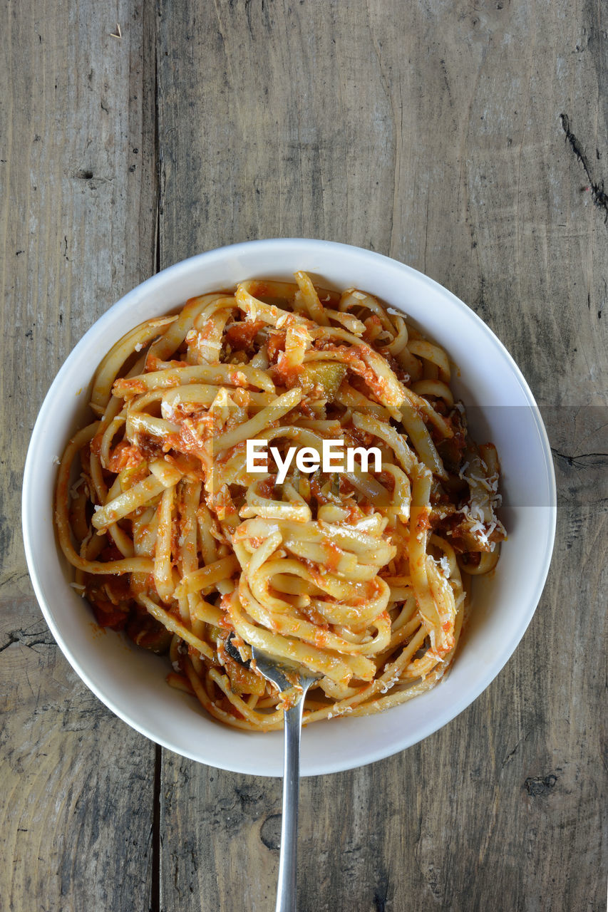 Linguine with tomato sauce and grated cheese on wooden table