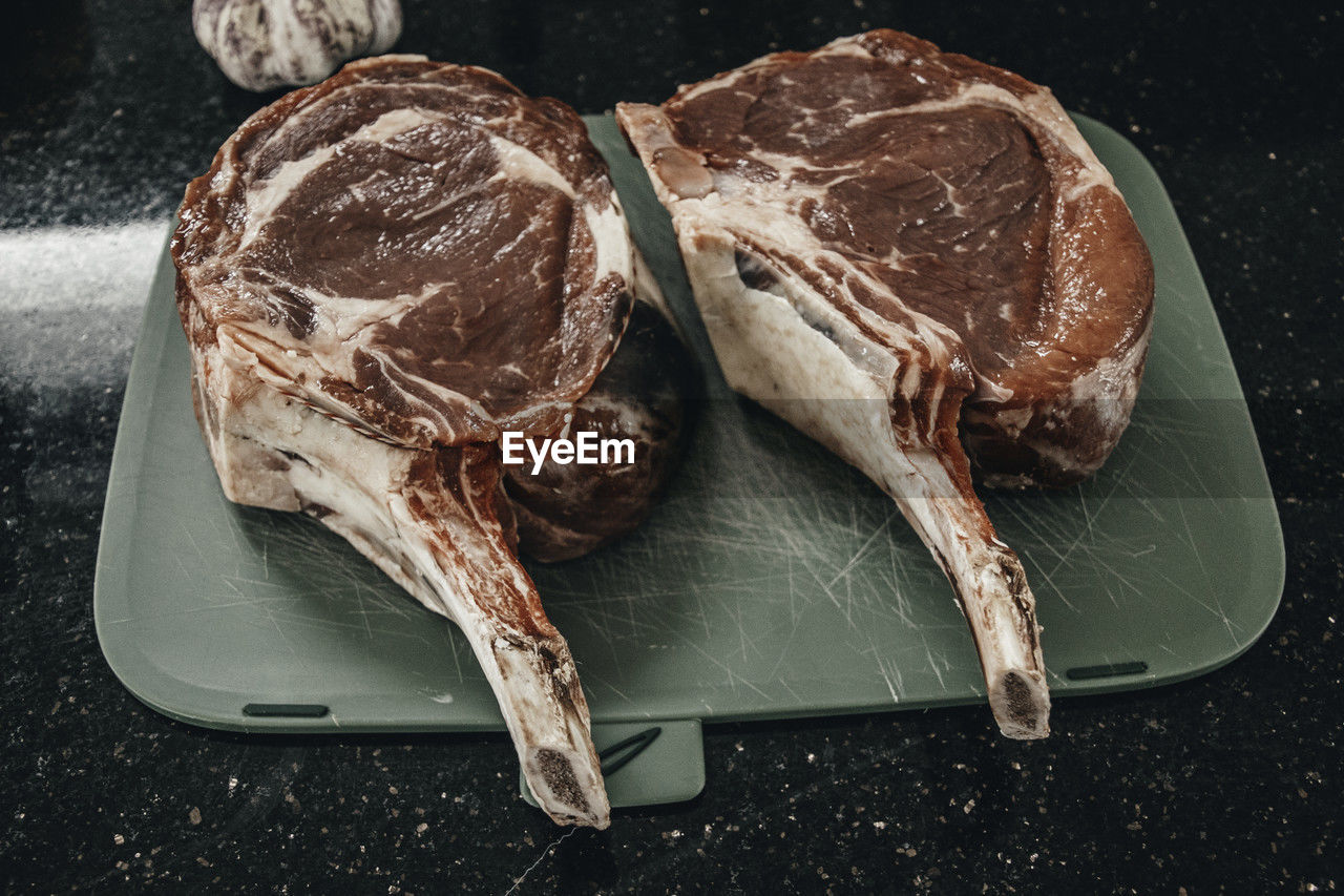 Two cuts of rib eye beef steak on cutting board