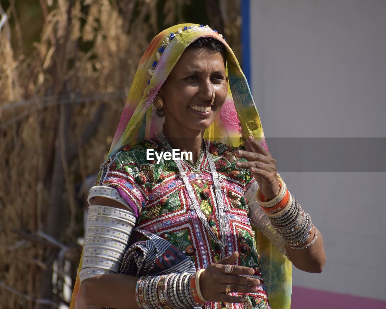 PORTRAIT OF A SMILING YOUNG WOMAN HOLDING CAMERA OUTDOORS