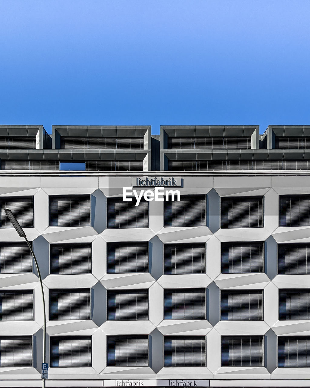 LOW ANGLE VIEW OF MODERN BUILDING AGAINST CLEAR BLUE SKY