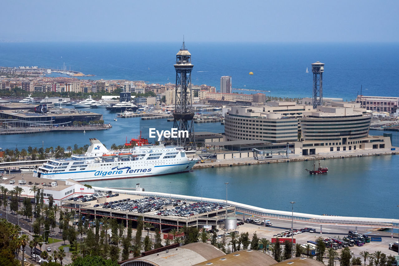 HIGH ANGLE VIEW OF SHIP MOORED AT HARBOR AGAINST BUILDINGS