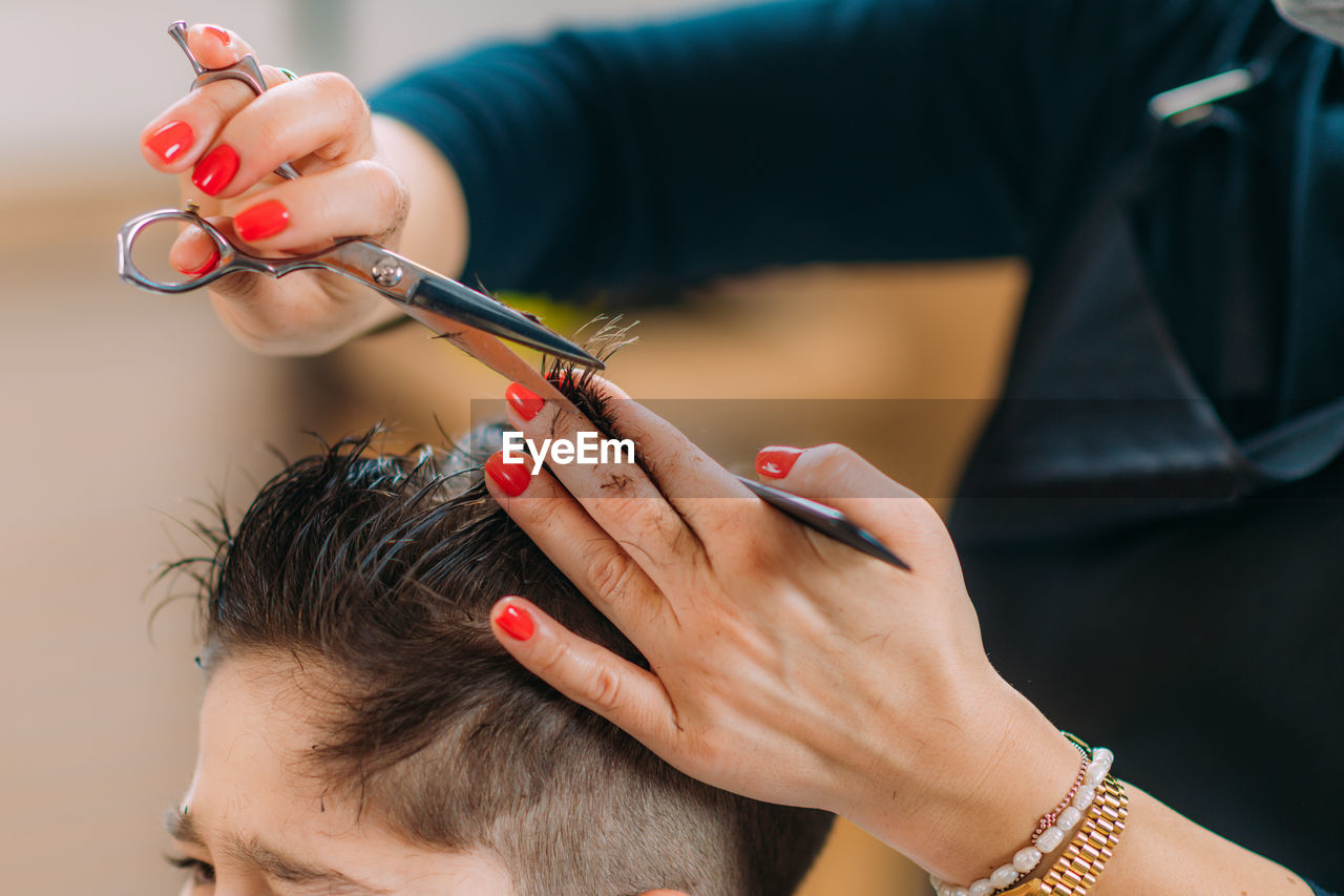 Little boy getting his hair cut by a female hairdresser in a hair salon for children.