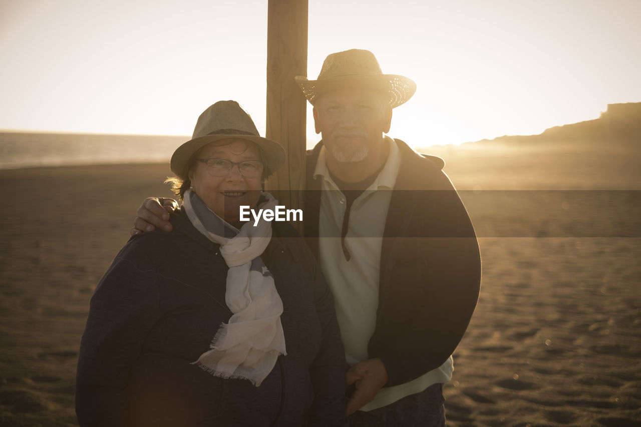 Portrait of couple standing at beach against sky
