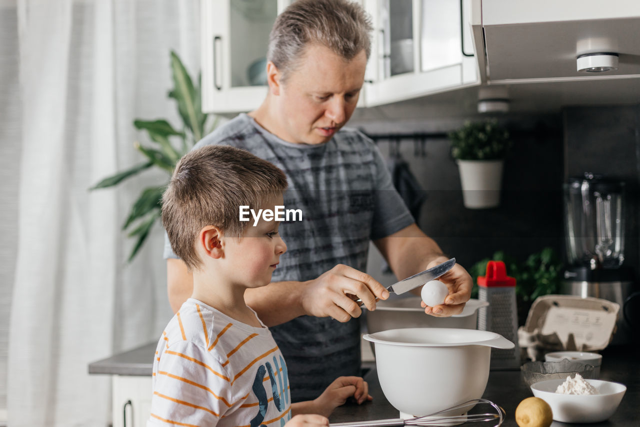 Man with boy preparing food in kitchen