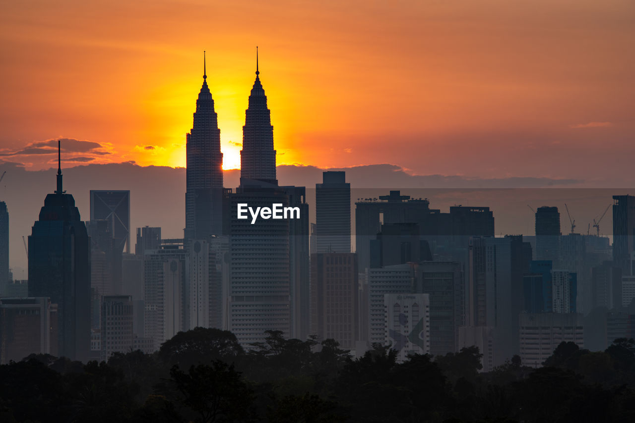 Modern buildings against sky during sunset