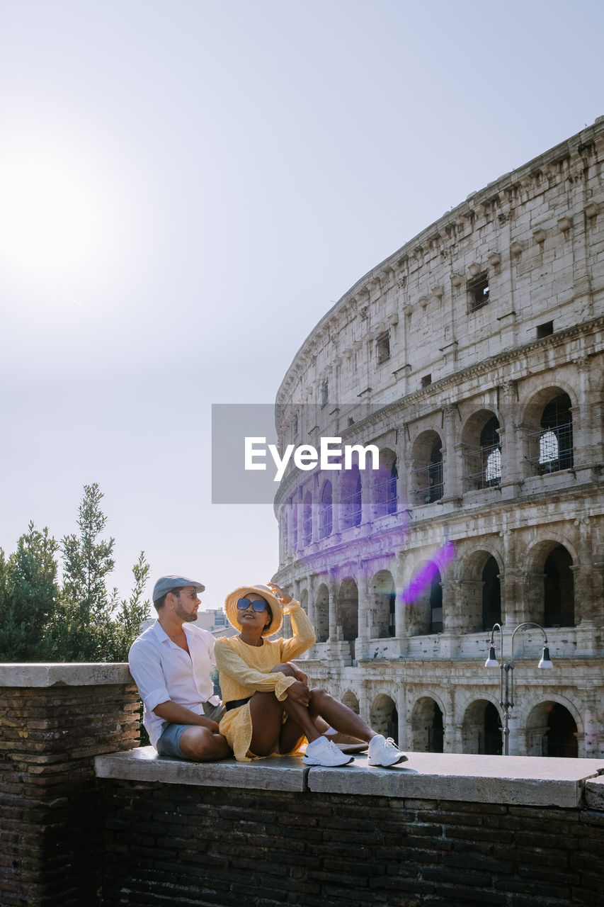 Couple sitting against ancient built structure